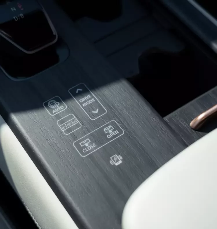 Pormenor da consola central do Nissan Ariya com botões táteis retroiluminados para modo de condução, e-Pedal e abertura automática do compartimento