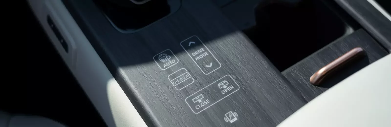 Pormenor da consola central do Nissan Ariya com botões táteis retroiluminados para modo de condução, e-Pedal e abertura automática do compartimento
