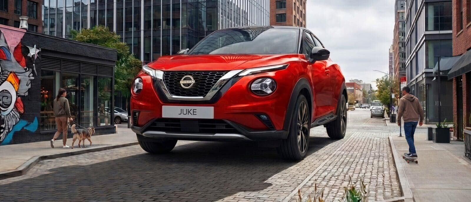 Nissan Juke em tamanho grande no meio de uma rua, com transeuntes a caminharem. 