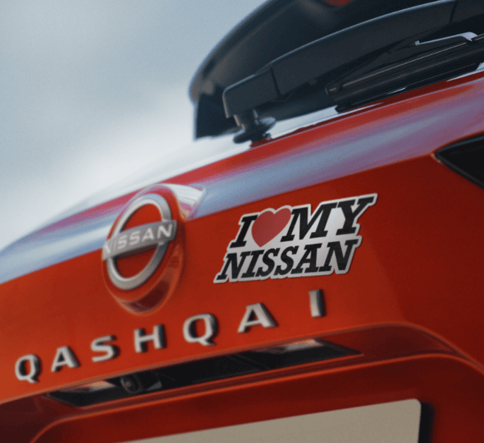 Nissan Qashqai em movimento numa avenida urbana, junto a um outdoor da campanha Fan Day.