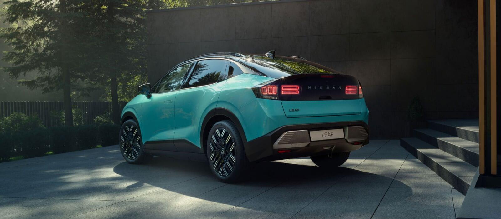 Vista traseira do novo Nissan LEAF, em azul teal, parado no exterior de uma casa minimalista. Em plano de fundo vemos uma floresta verde. 