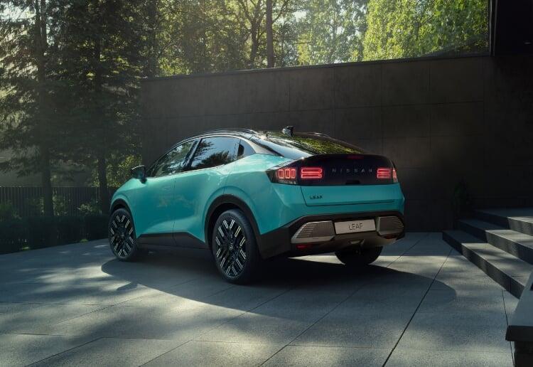 Vista traseira do novo Nissan LEAF, em azul teal, parado no exterior de uma casa minimalista. Em plano de fundo vemos uma floresta verde. 