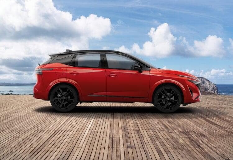 Nissan Qashqai usado certificado, em tonalidade vermelha, num passadiço de madeira. Atrás do carro vemos o mar e a costa.